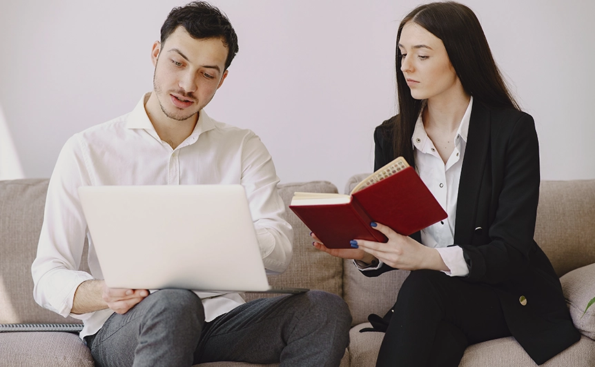 Two Professionals Discussing Documents and Notes on a Sofa