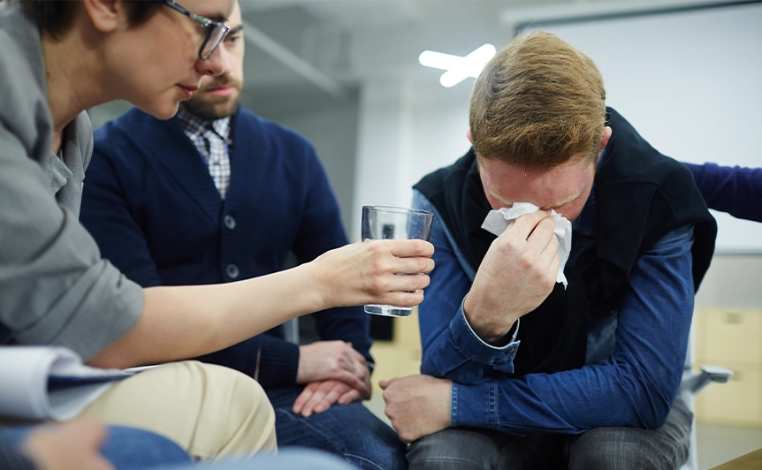 Group Therapy Session with Man Crying and Supportive Participants Nearby