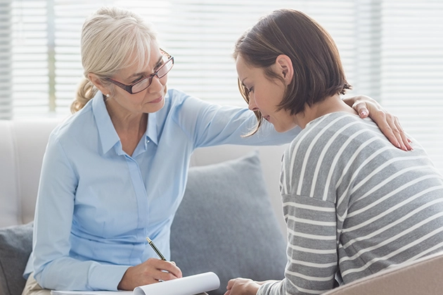 Older woman comforting younger woman during a counseling session on a couch.
