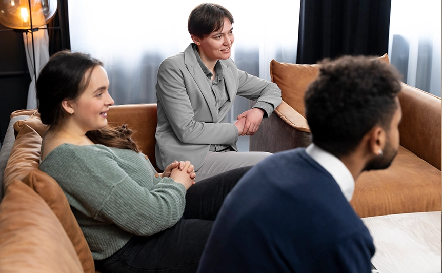 Three people sitting on a couch, engaged in conversation.