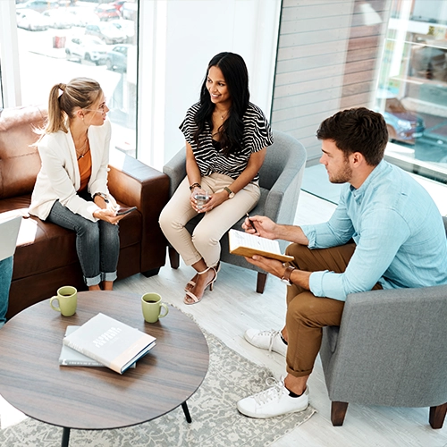 Three people sitting together in a bright office having a discussion.