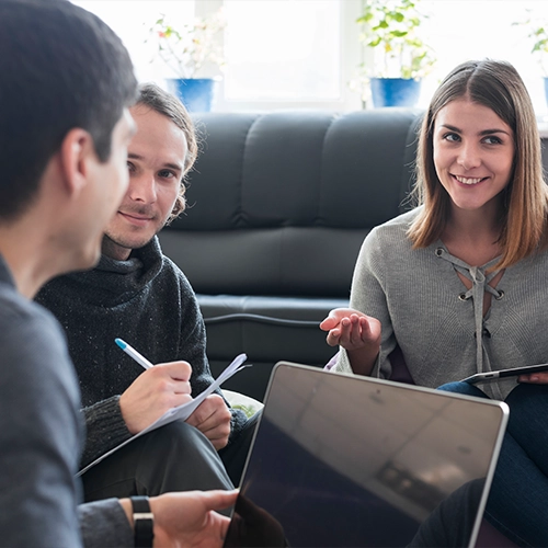 Three people having a discussion in a cozy living room setting.